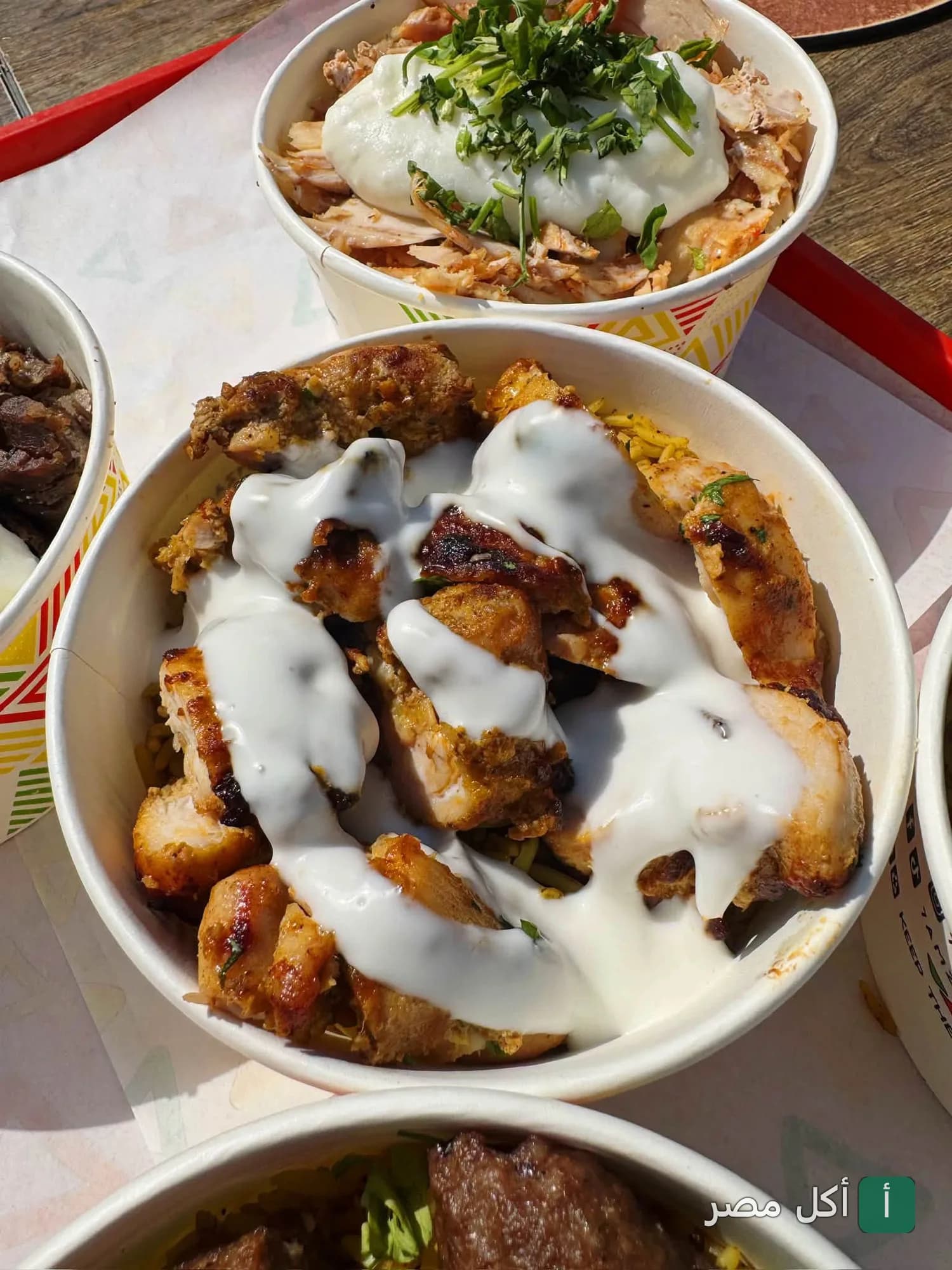 أطباق أرز بالدجاج المشوي مغطاة بصوص الثومية في مطعم حمزة بمدينة 6 أكتوبر.