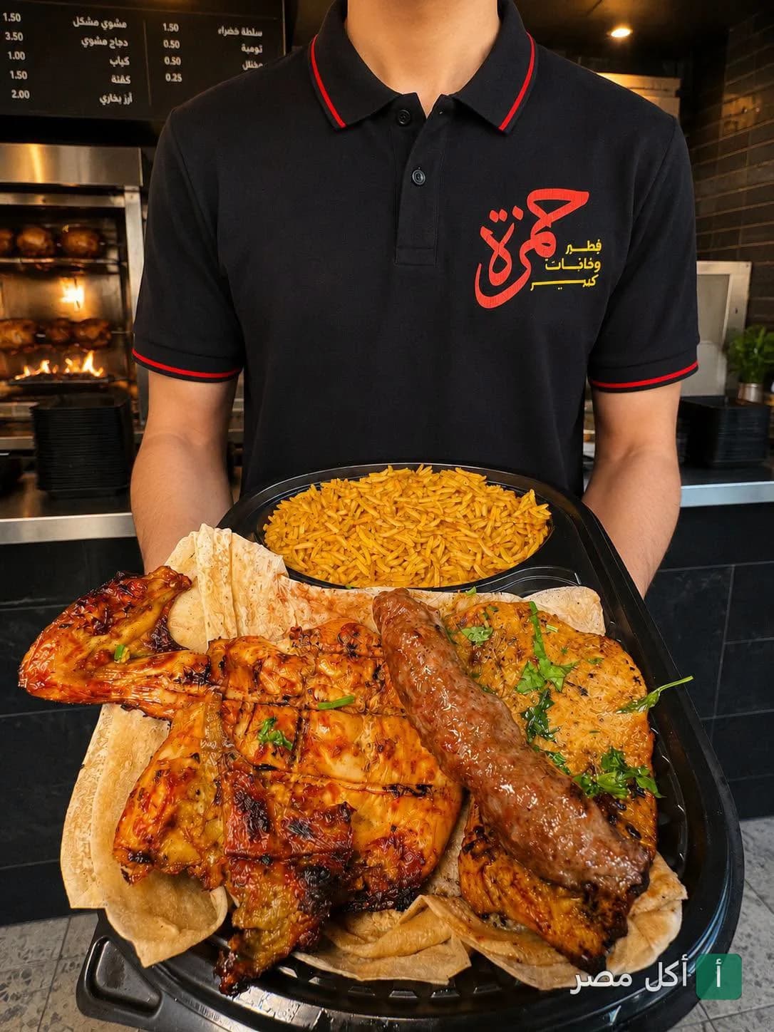 موظف مطعم حمزة في 6 أكتوبر يقدم طبق مشويات مشكل مع أرز في صينية.