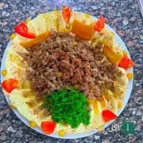 طبق حمص باللحمة المفرومة مزين بالبقدونس والطماطم من مطعم الشعلان في 6 أكتوبر.
