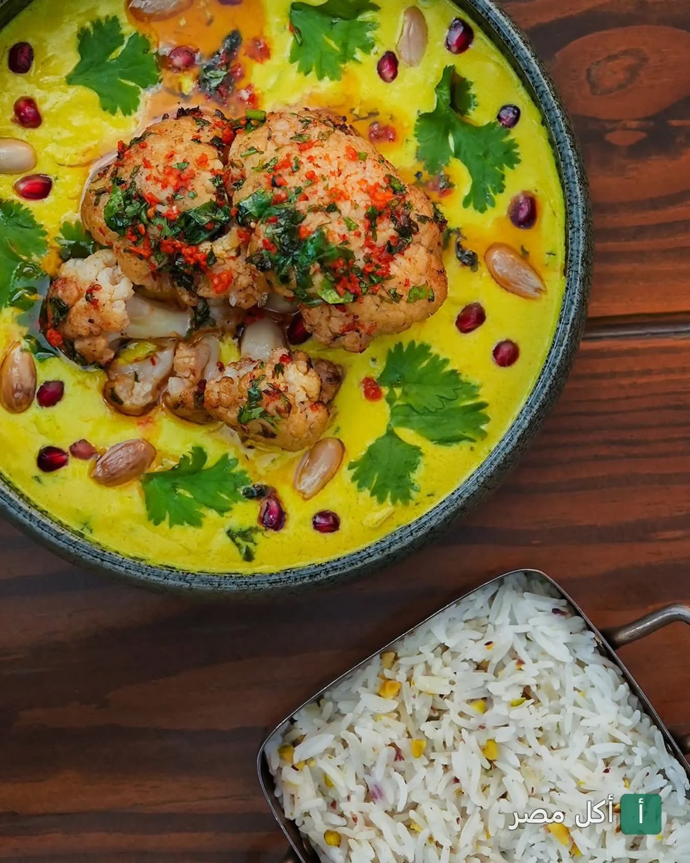 طبق قرنبيط بصوص أصفر مزين بالرمان والكزبرة مع طبق أرز جانبي في مطعم مايريك بمدينة 6 أكتوبر.