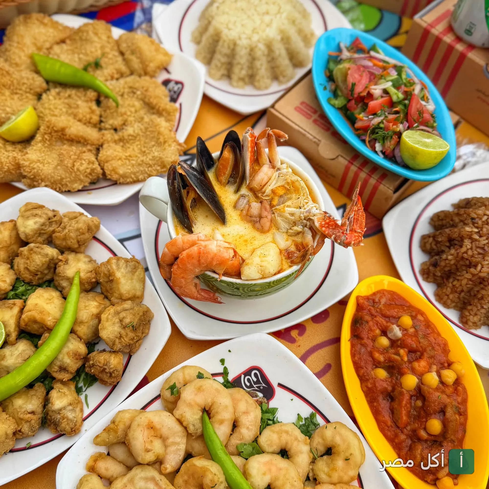سفرة مأكولات بحرية متنوعة من مطاعم جحا في 6 أكتوبر، تشمل شوربة سي فود، جمبري مقلي، سمك مقلي، وأرز.