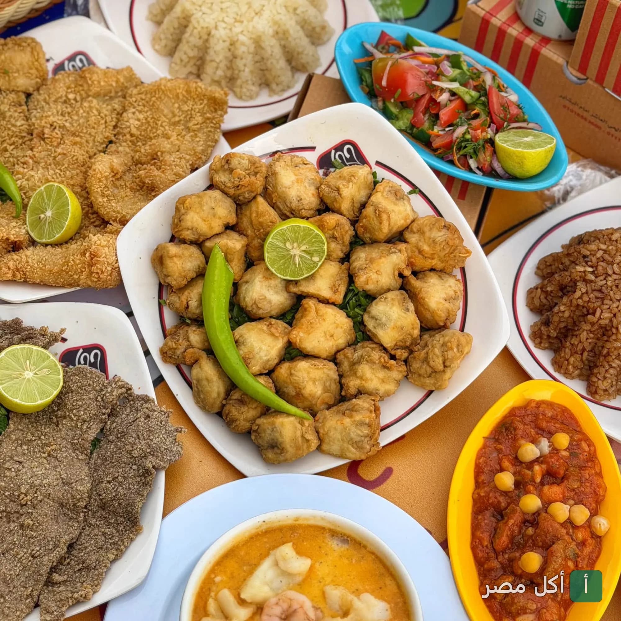 سفرة متنوعة من مطاعم جحا في 6 أكتوبر تضم أطباق مقلية، أرز، سلطة خضراء، وطاجن بالصلصة.