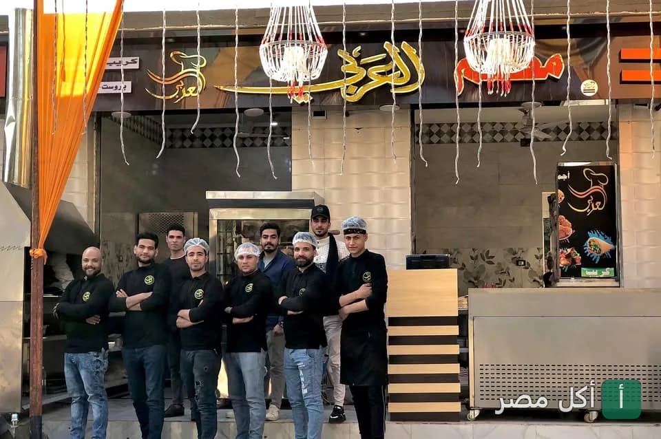 فريق عمل مطعم عرب بني صالح في أطفيح يقفون أمام واجهة المطعم.