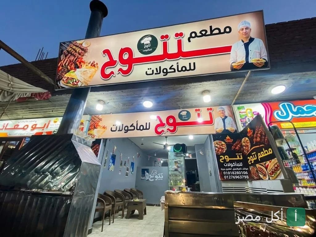واجهة مطعم تتوح للمأكولات في أطفيح مع لافتات تعرض صور المشويات والساندوتشات
