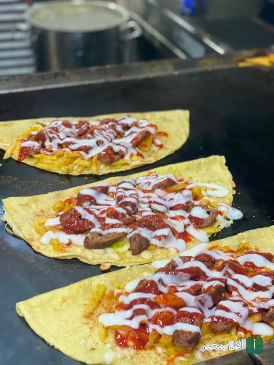 ساندوتشات كريب بالسجق والبطاطس مع صوص الكاتشب والمايونيز على الجريل في مطعم تتوح بأطفيح