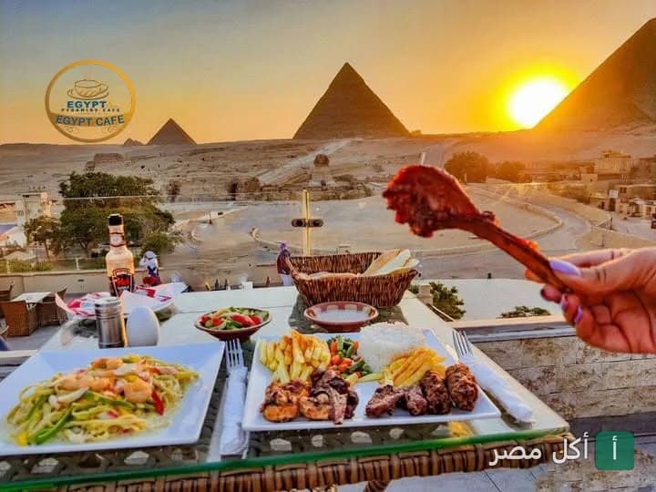 أطباق مشويات ومكرونة على طاولة تطل على أهرامات الجيزة وقت الغروب في مطعم بيراميدز.