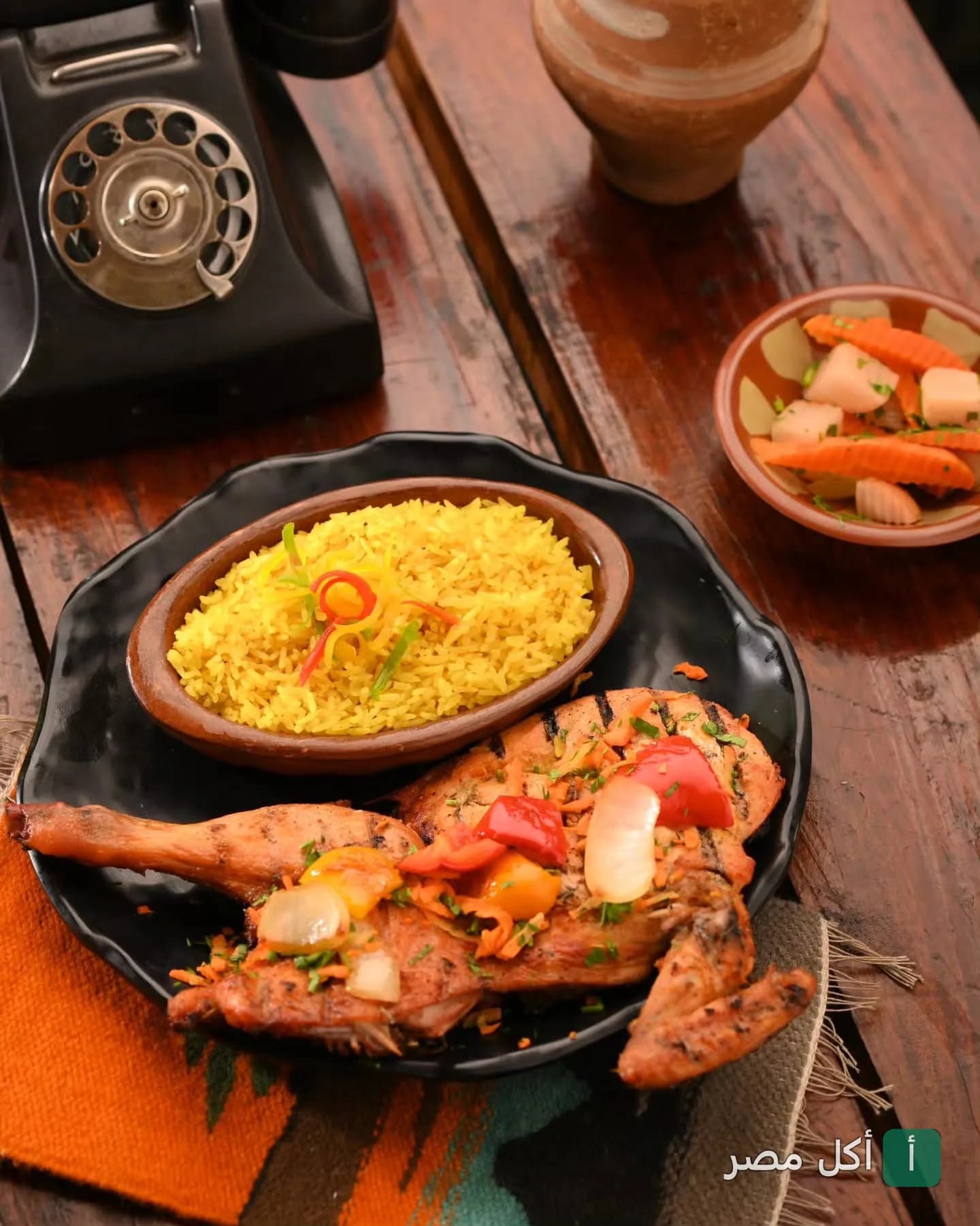طبق دجاج مشوي مع أرز أصفر ومخلل في مطعم الكوخ بالكوربة
