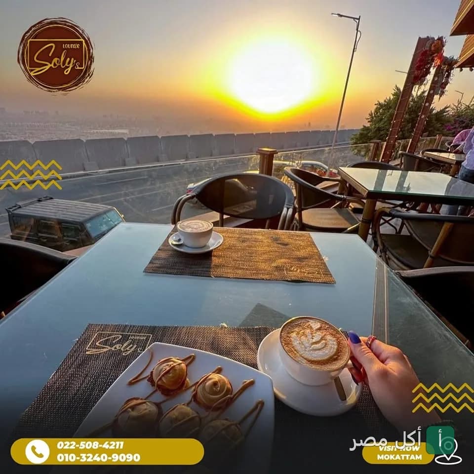 غروب الشمس من تراس مطعم سولي بالمقطم مع قهوة وحلويات على الطاولة.