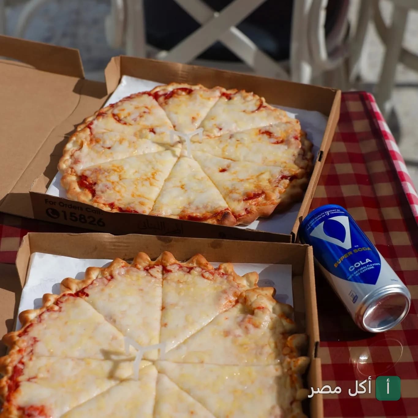 بيتزا بالجبنة في علب كرتون مع مشروب غازي على طاولة في المخبز اللبناني الأصلي.