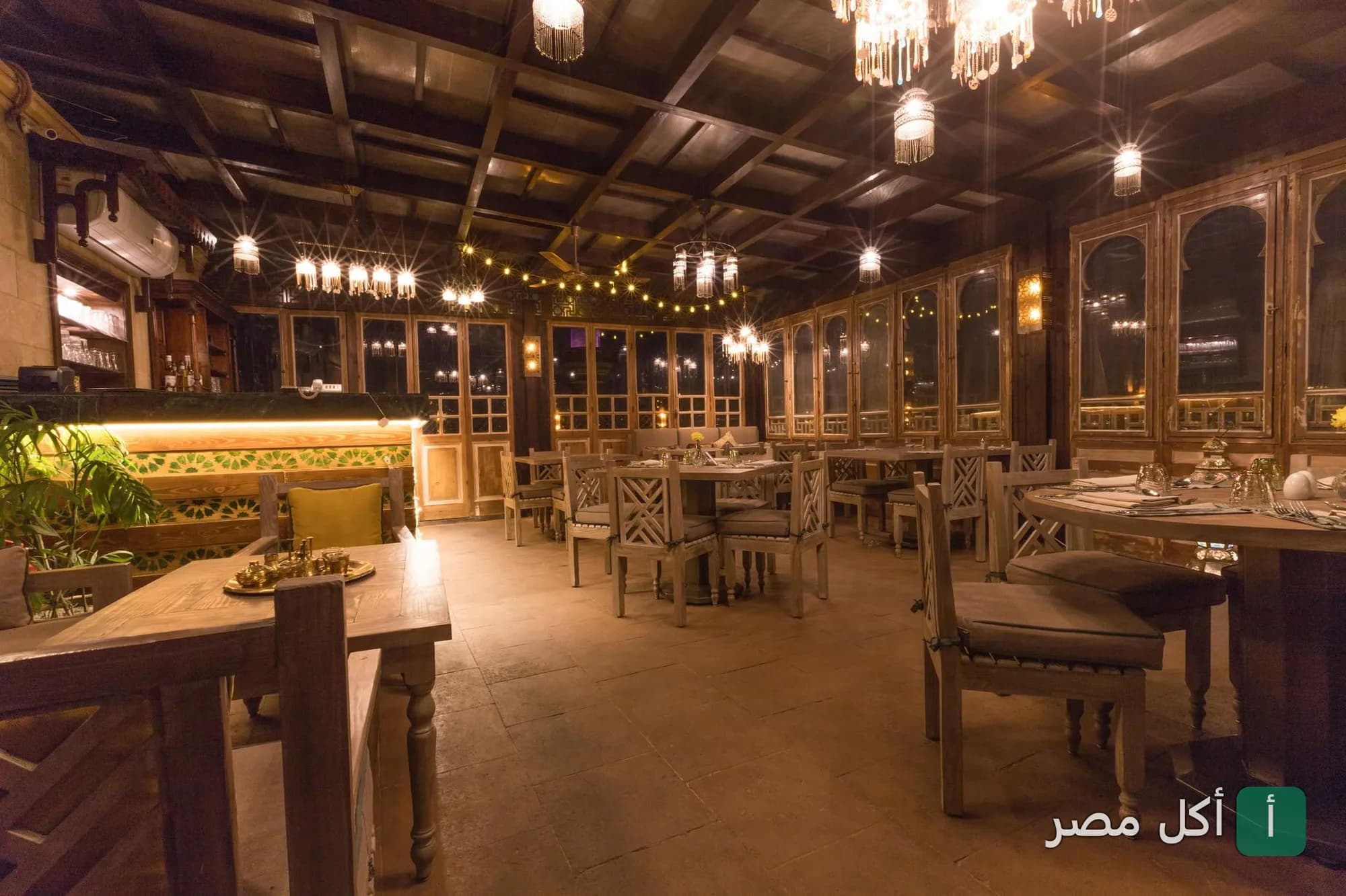 ديكور داخلي دافئ لمطعم زيارة أهرامات النخبة في الجيزة مع إضاءة خافتة وأثاث خشبي.