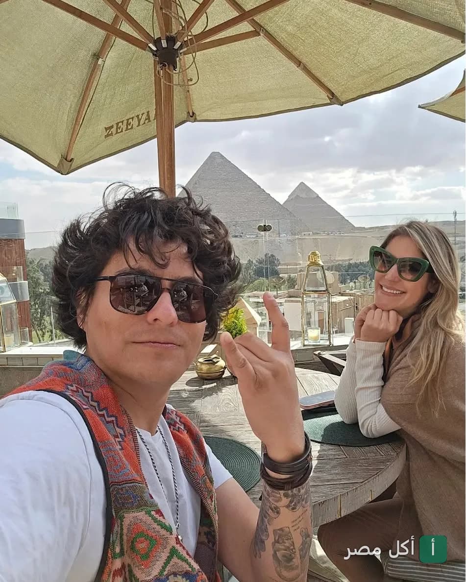 شخصان يجلسان في مطعم زيارة بيراميدز إيليت مع إطلالة مباشرة على الأهرامات.