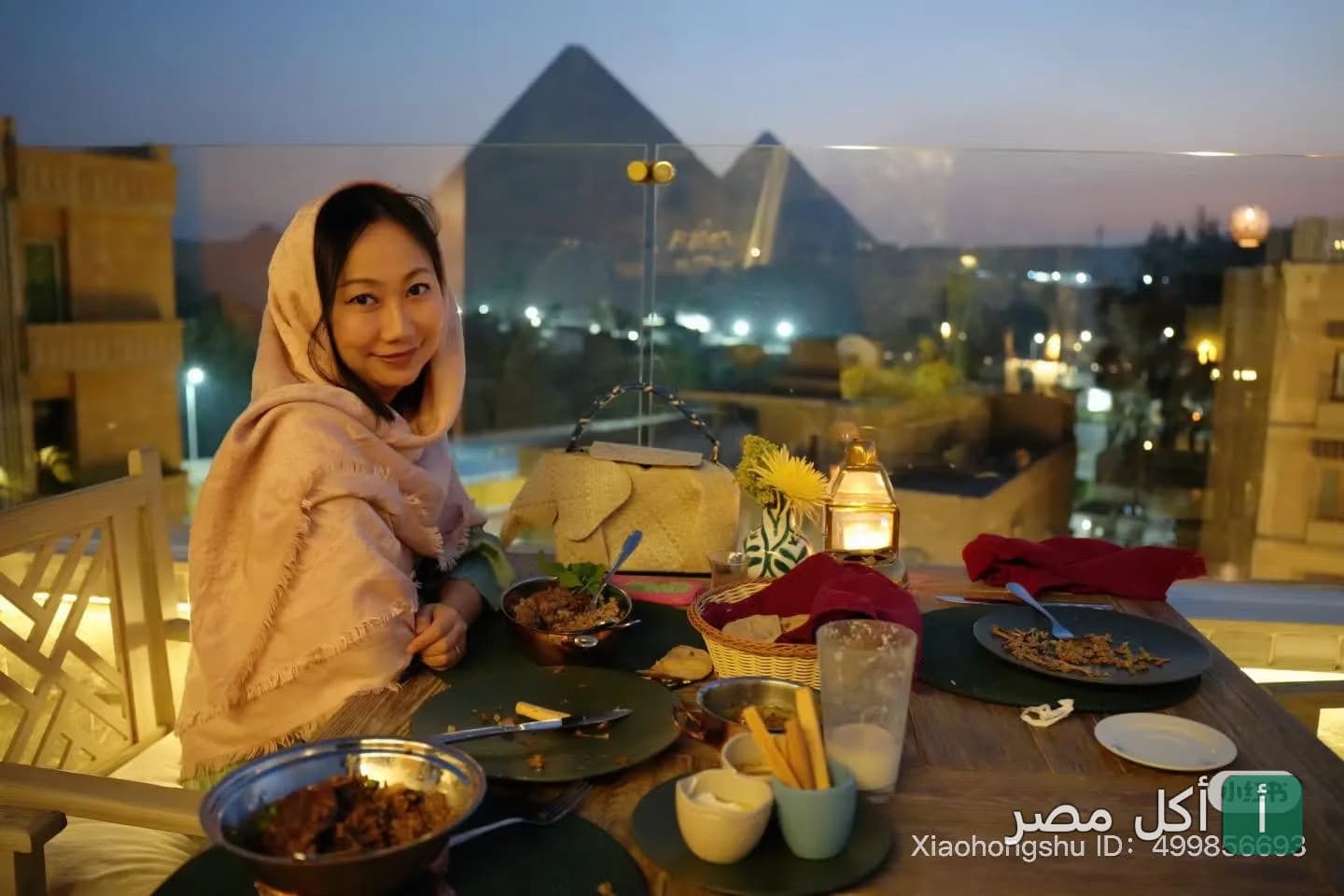 زبونة تجلس في مطعم زيارة بيراميدز إيليت مع إطلالة مباشرة على الأهرامات وقت الغروب.