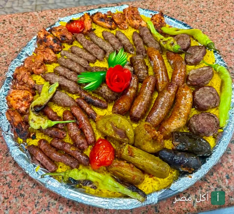 صينية مشويات مشكلة تضم كفتة، سجق، وقطع دجاج على أرز أصفر في مطعم رغيف بابا بمصر الجديدة.