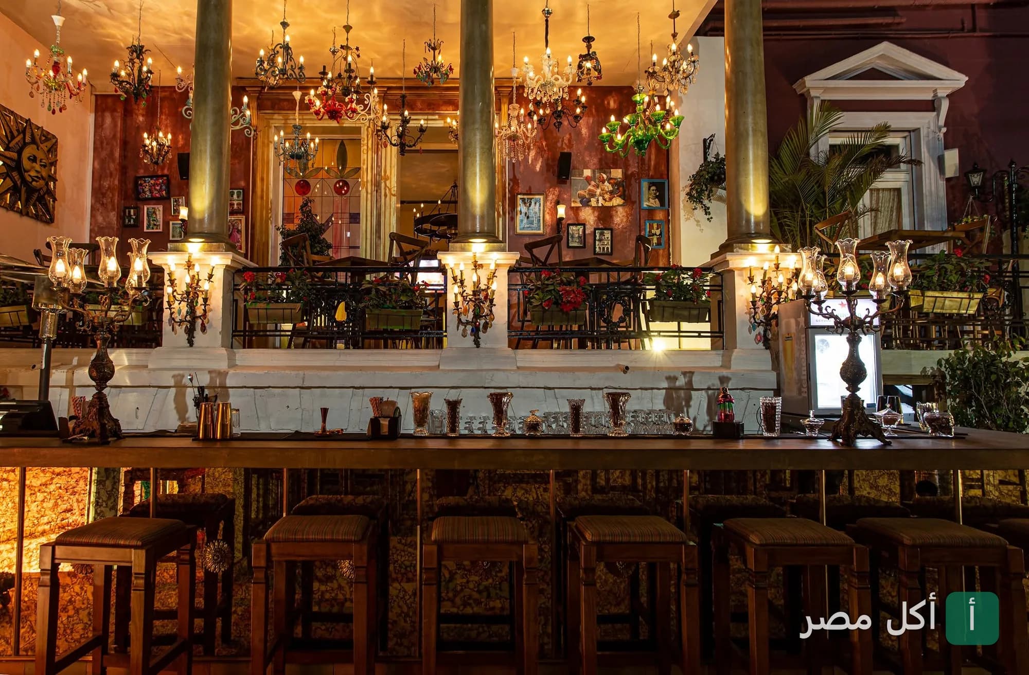 ديكور داخلي لمطعم EL BARRIO EGYPT في الماظة، يظهر بار خشبي مع كراسي مرتفعة وإضاءة كلاسيكية متدلية.