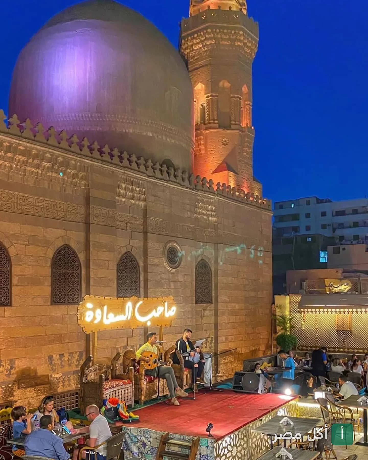 أجواء مسائية في مطعم صاحب السعادة بفرع المعز مع عرض موسيقي حي أمام مسجد تاريخي.