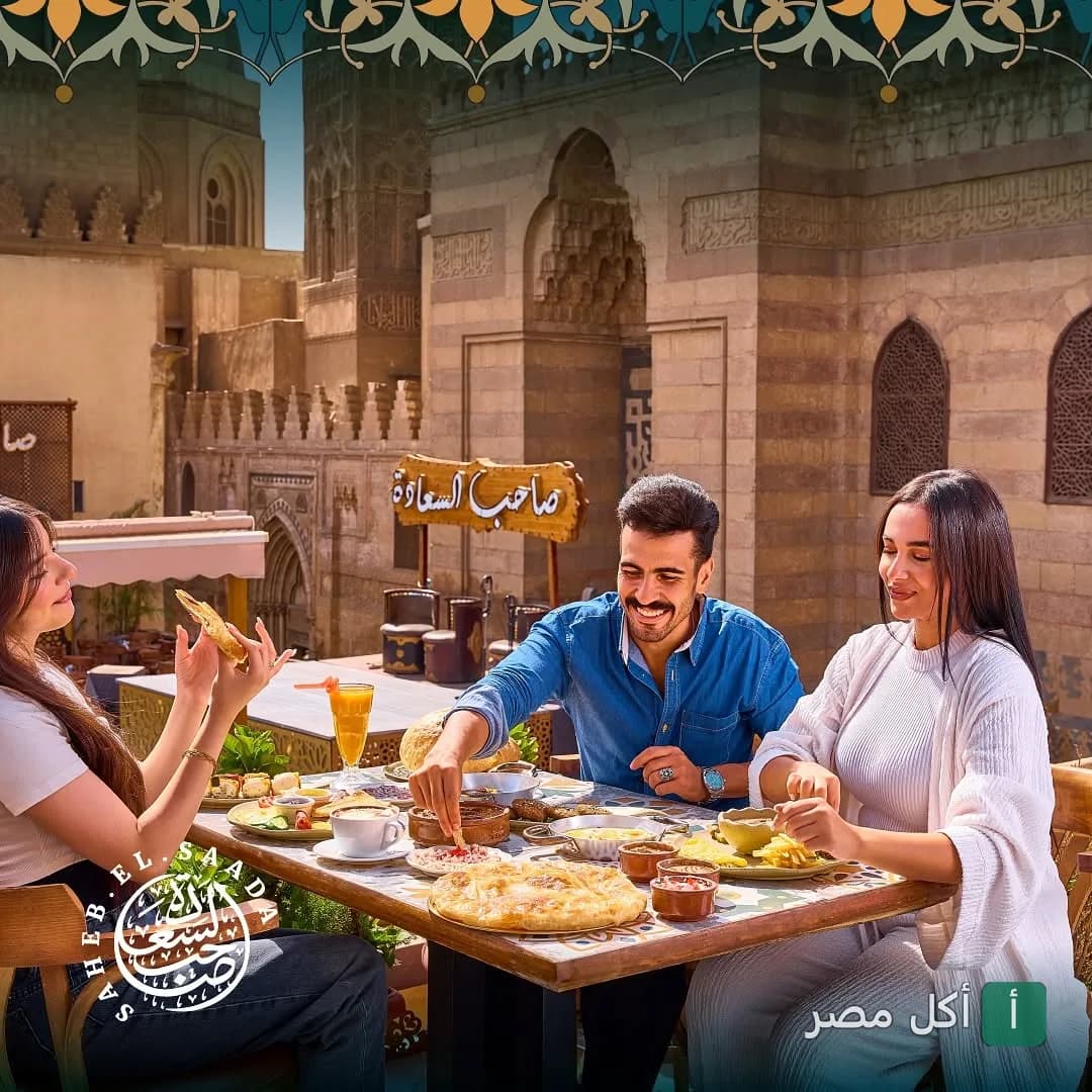مجموعة من الأصدقاء يتناولون الطعام في مطعم صاحب السعادة فرع المعز مع خلفية تاريخية.