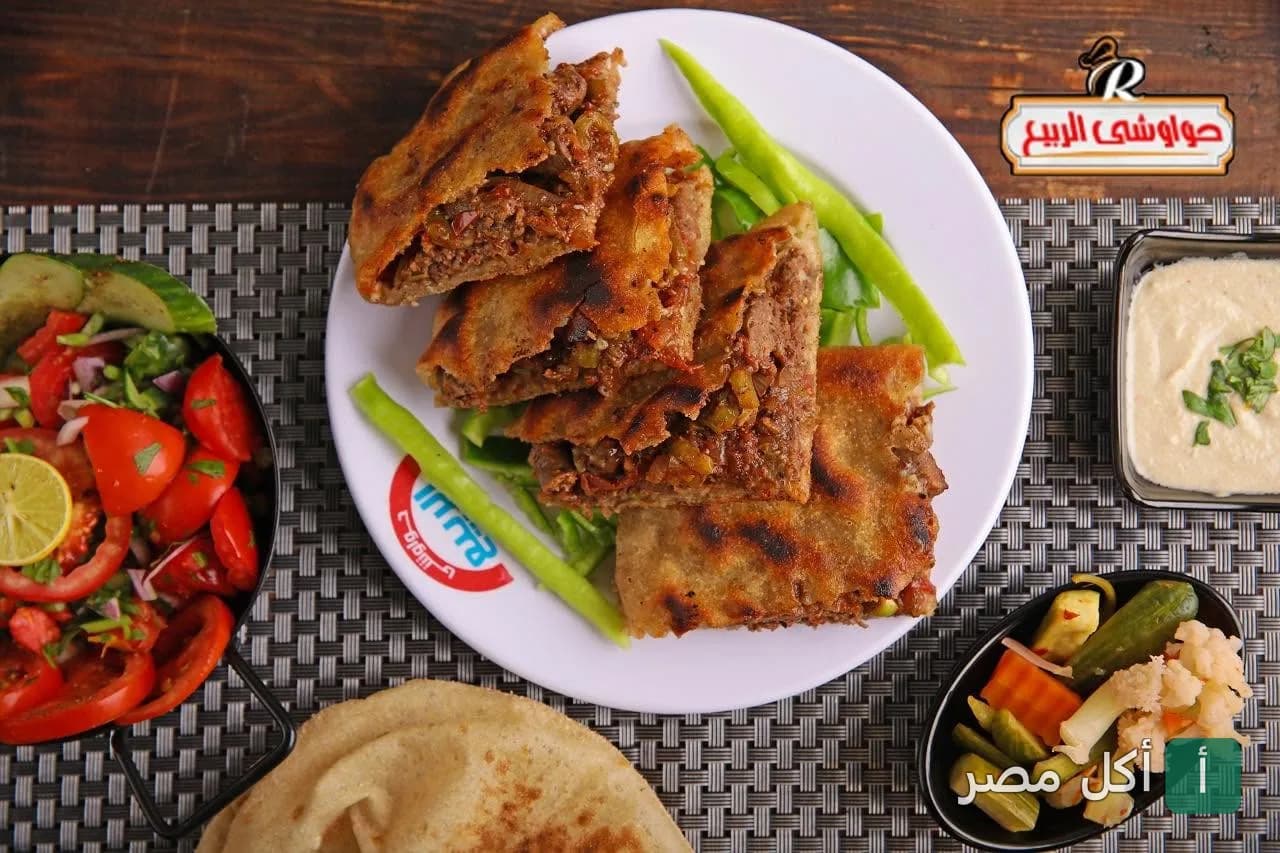 طبق حواوشي مصري ساخن مع سلطة خضراء وطحينة ومخلل من مطعم حواوشي الربيع بإمبابة.
