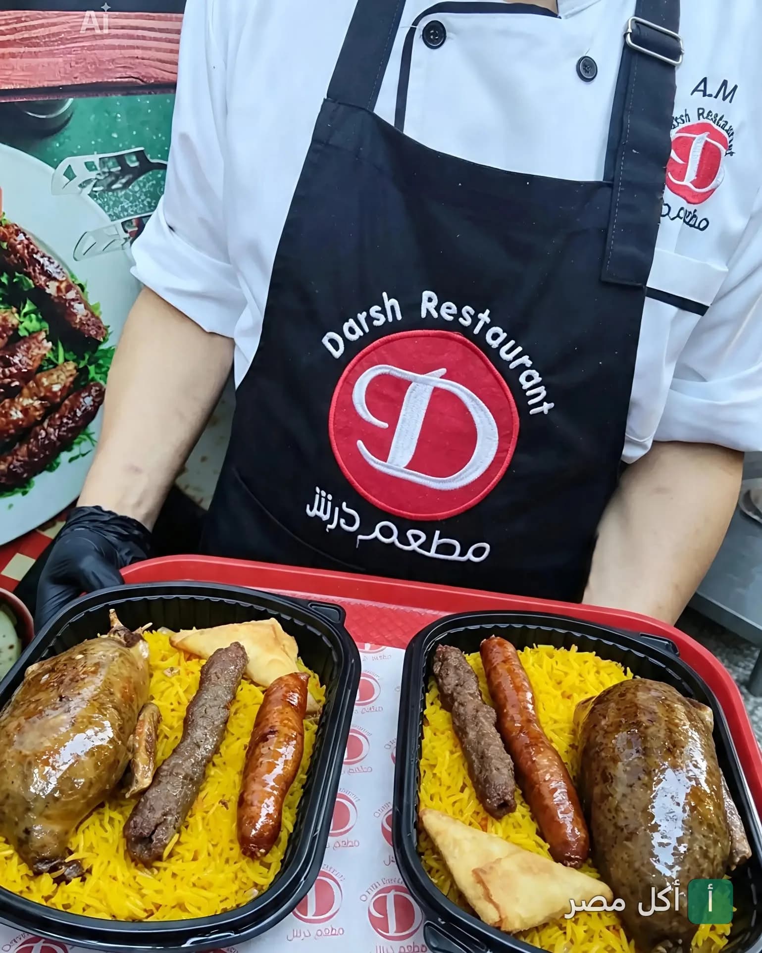 شيف يرتدي مريلة مطعم درش إمبابة يقدم وجبات أرز شرقي مع كفتة وسجق وحمام محشي.