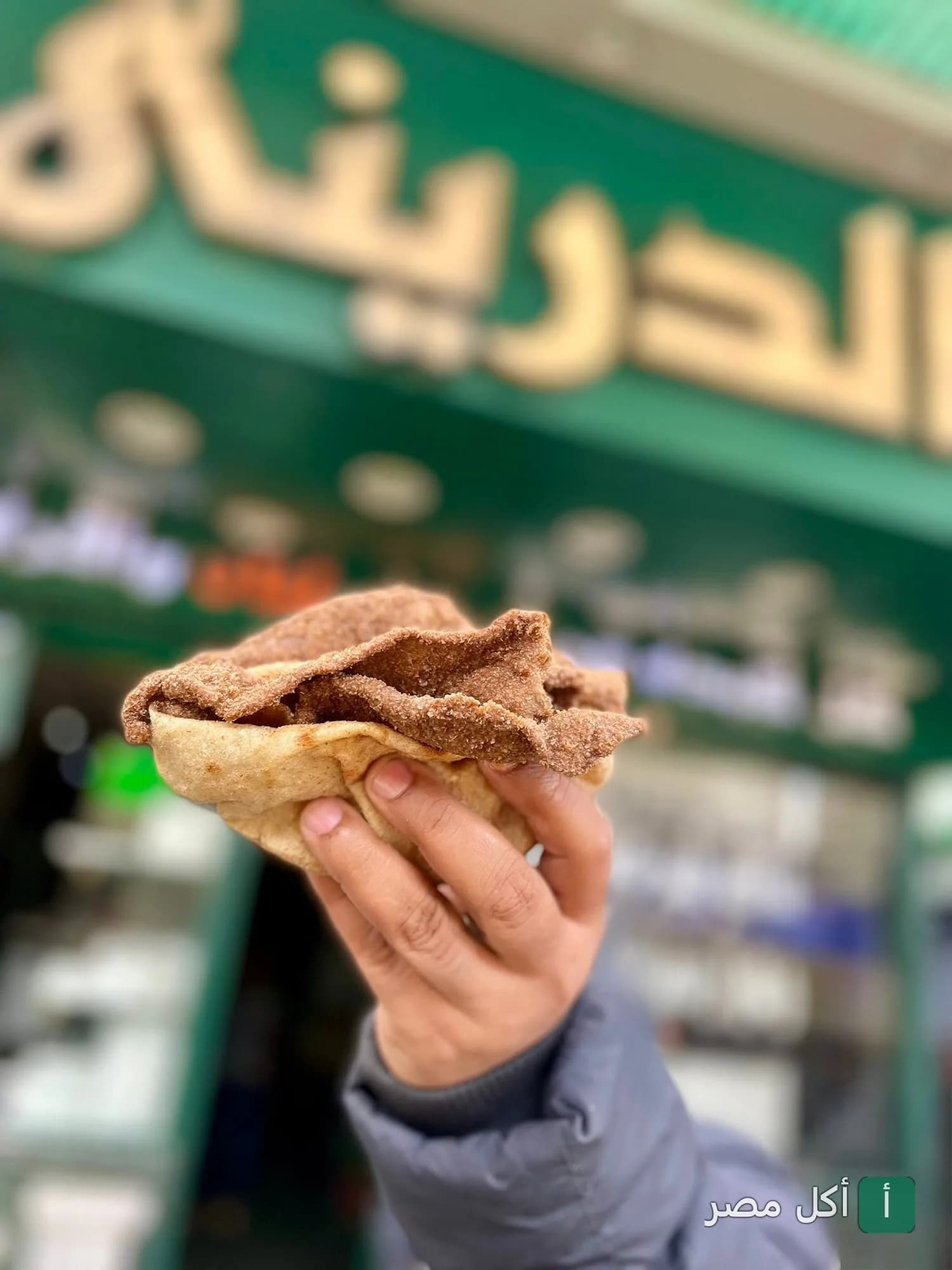 ساندوتش كبدة في خبز بلدي أمام واجهة مطعم كبدة ومخ الدريني في جزيرة إمبابة.