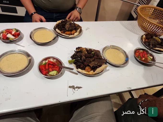 مائدة طعام تحتوي على أطباق مشويات شرقية ومقبلات وسلطة طحينة في مسمط تبارك بالمنيرة في إمبابة.