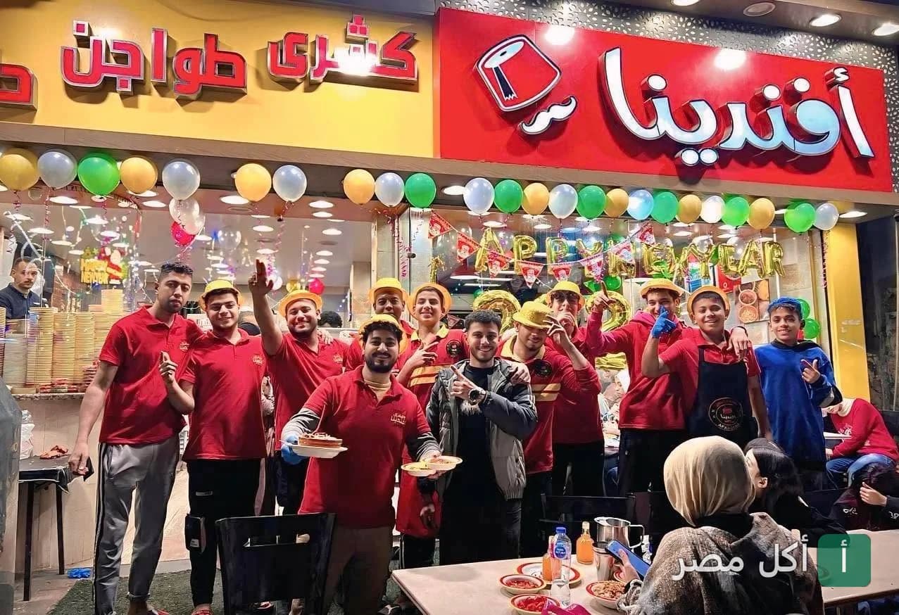 فريق عمل مطعم كشري وحلواني افندينا في إمبابة أمام واجهة المطعم المزينة بالبالونات.