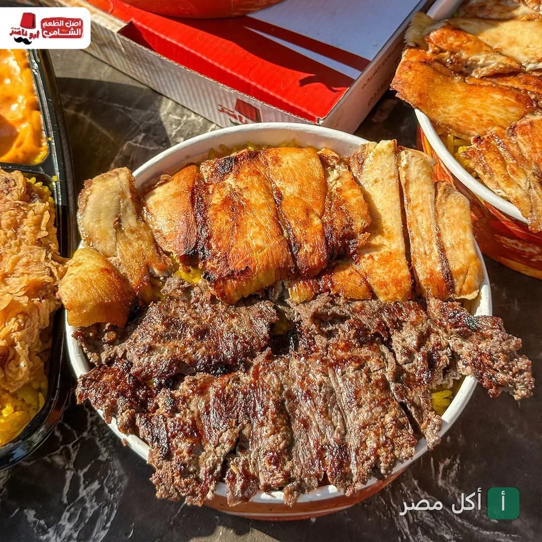 وجبة مشاوي مشكلة من مطعم أبو ناصر السوري في بشتيل، إمبابة، تتكون من قطع دجاج ولحم مشوي على أرز أصفر.