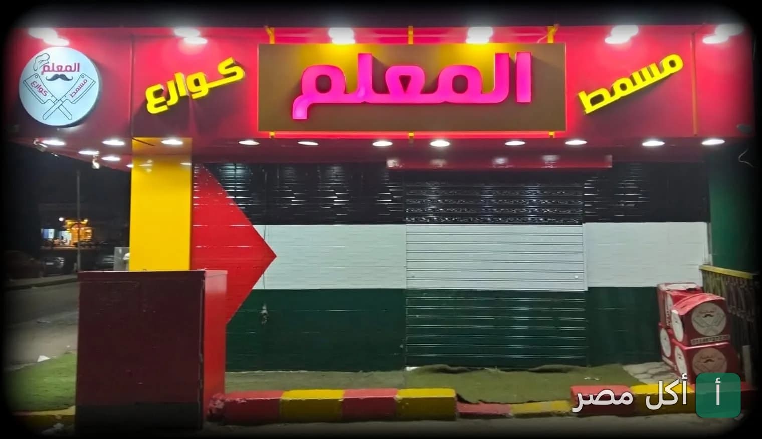 واجهة مسمط المعلم في منطقة البوهي بإمبابة، تظهر اللافتة المضيئة واسم المطعم بوضوح.