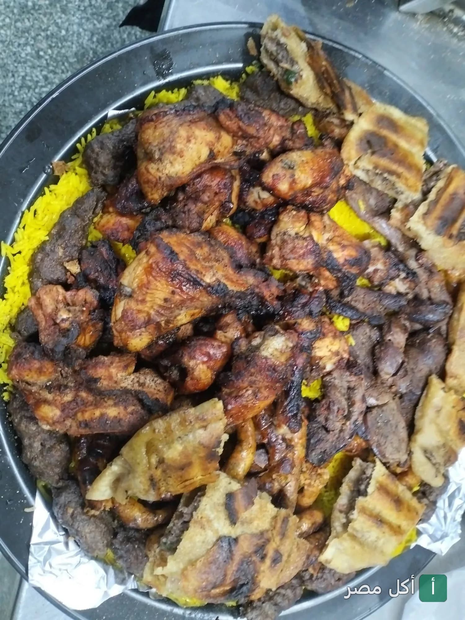طبق مشويات مصري متنوع يضم قطع دجاج وكفتة على أرز أصفر في مطعم كبابجي أبو غنيمة بإمبابة.