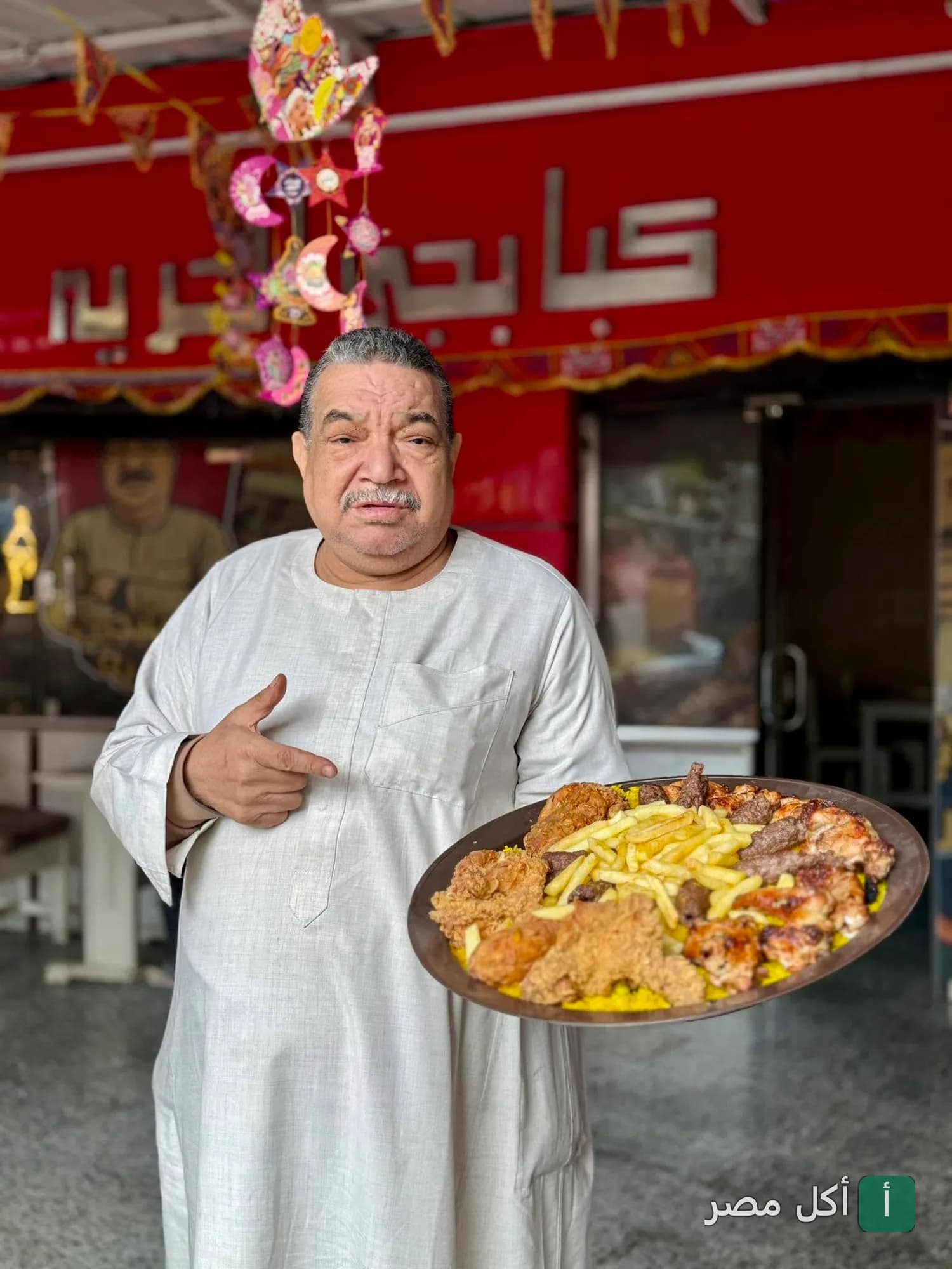 صاحب مطعم كبابجي الحرية في إمبابة يحمل صينية مشاوي مشكلة مع أرز وبطاطس مقلية.