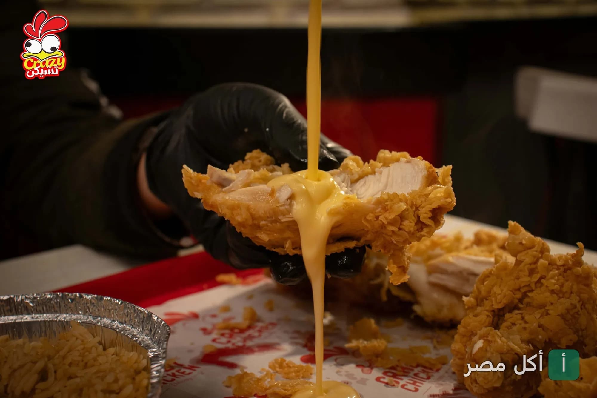 صب صوص الجبنة السايحة على قطعة دجاج مقرمشة في مطعم كريزي تشيكن ببشتيل، إمبابة.