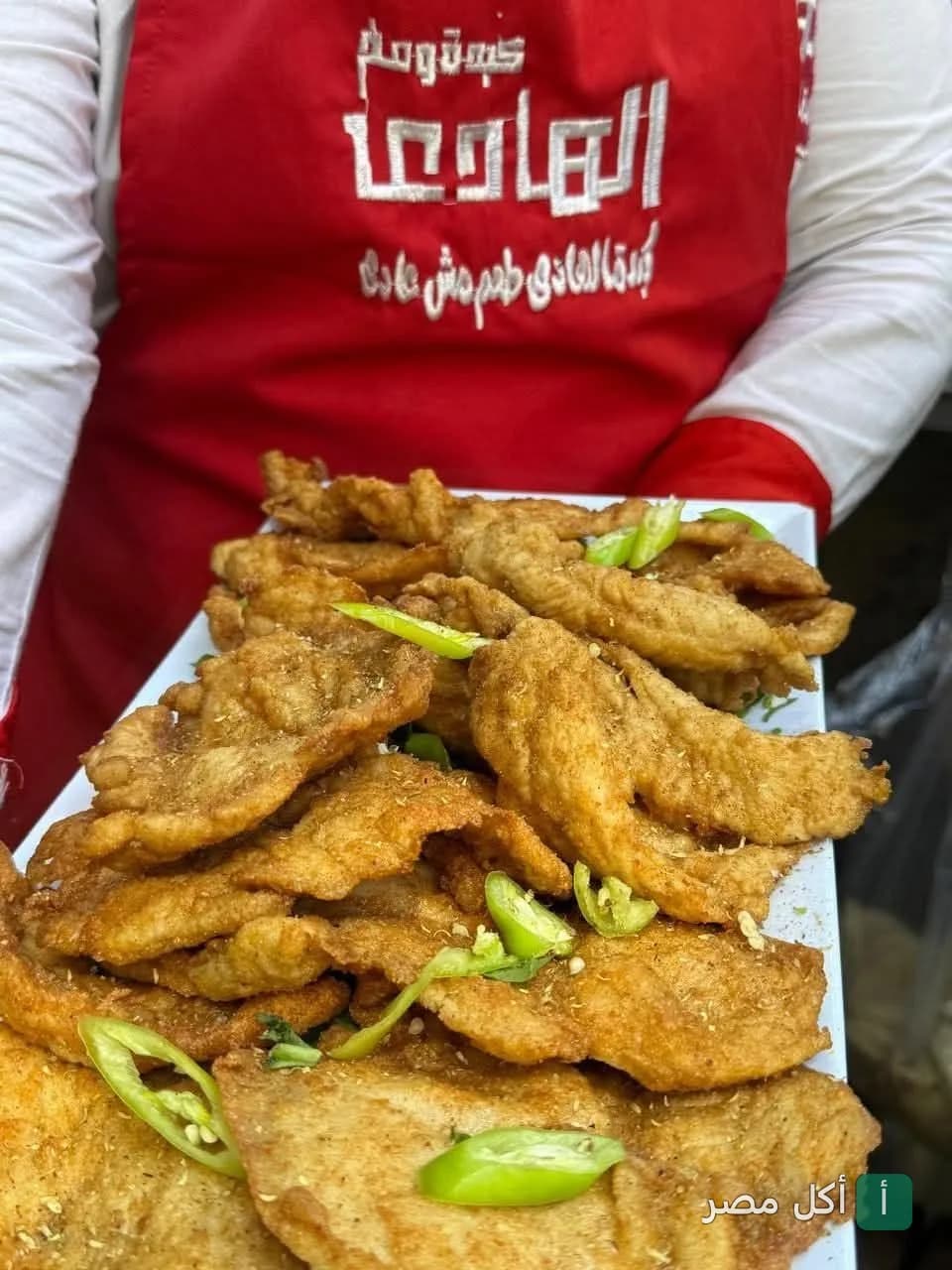 طبق كبدة مقلية يقدمه موظف يرتدي مريلة مطعم الهادي في إمبابة.