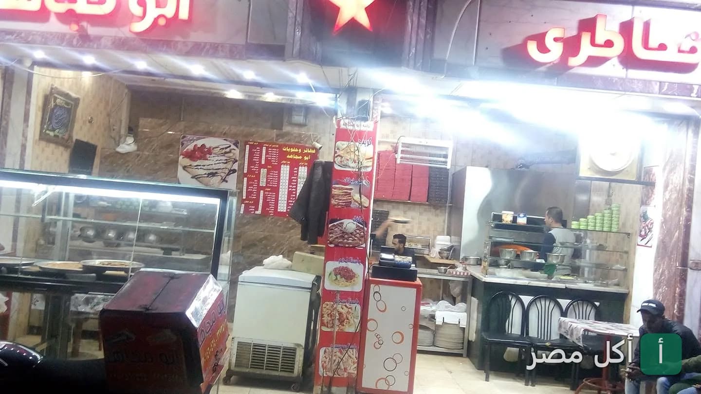 واجهة مطعم بيتزا وحلوانى وفطائر أبو مجاهد في شارع المطار بإمبابة، يظهر فيها قائمة الطعام وواجهة العرض.
