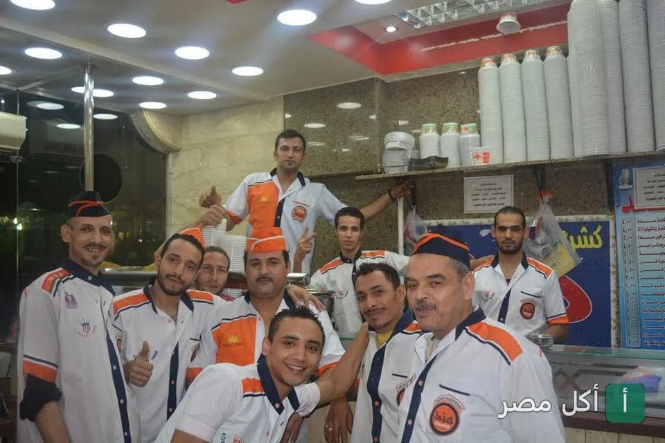 فريق عمل مطعم كشري هند في إمبابة بزي العمل الموحد داخل صالة المطعم.