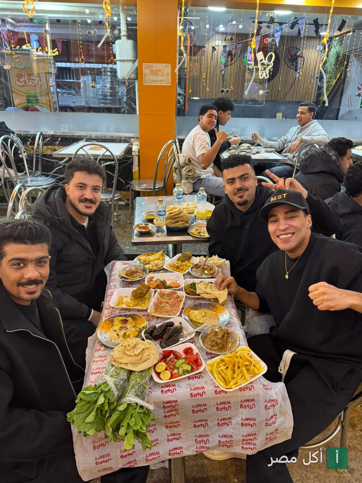مجموعة من الشباب يتناولون وجبة إفطار شرقية متنوعة في مطعم فول وفلافل نيو ومبى بإمبابة.
