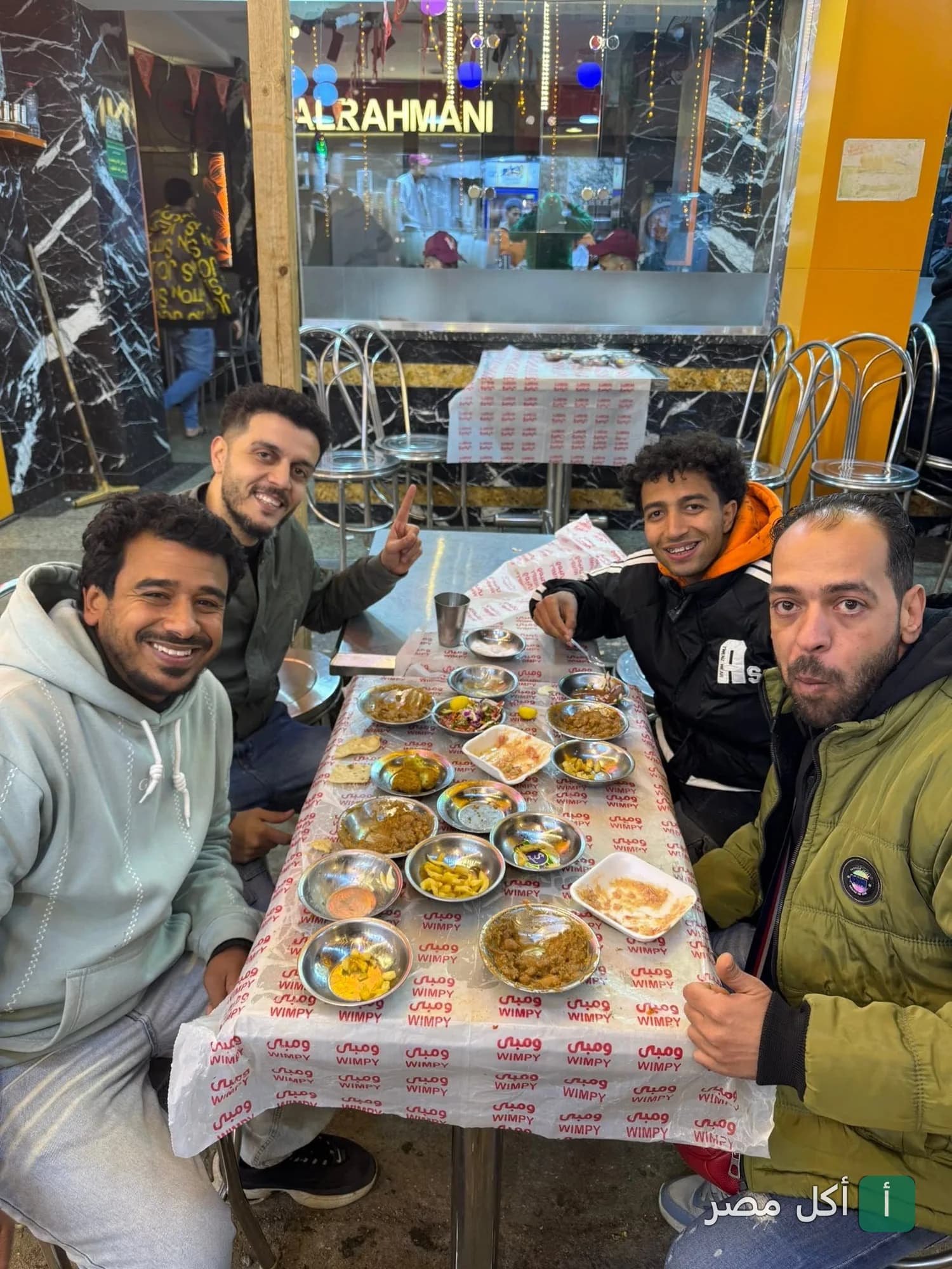 أصدقاء يتناولون وجبة إفطار شرقي متنوعة على طاولة في مطعم فول وفلافل نيو ومبى بإمبابة.