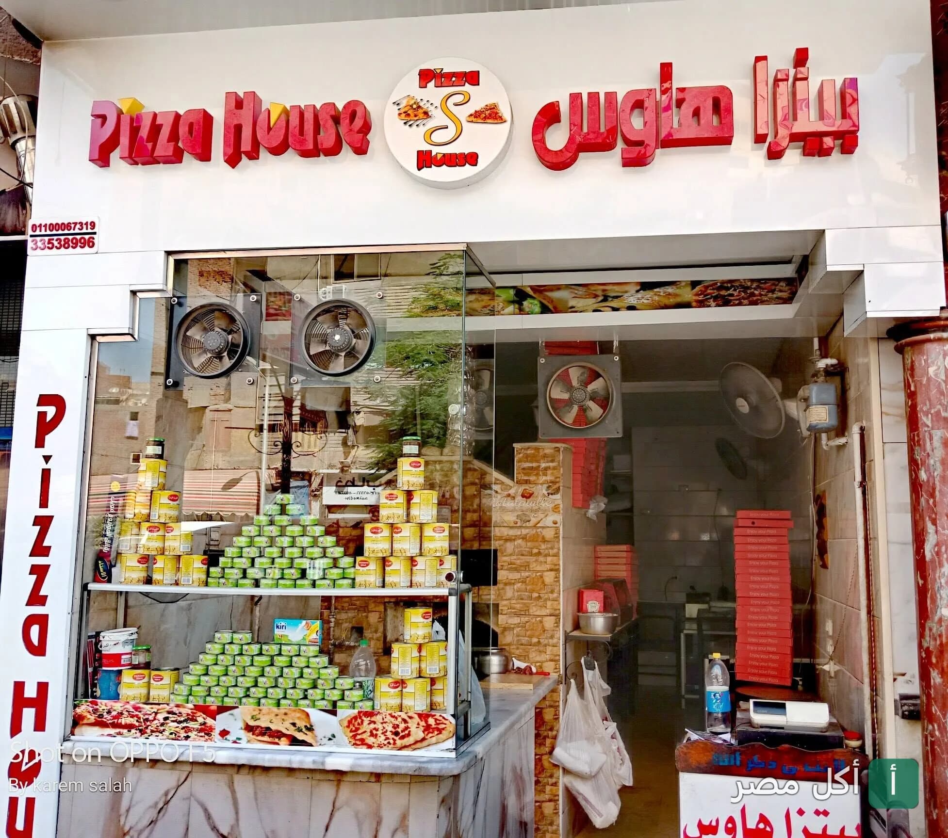 واجهة مطعم بيتزا هاوس في بشتيل بإمبابة، تظهر لافتة المطعم وعلب البيتزا المرصوصة بالداخل.