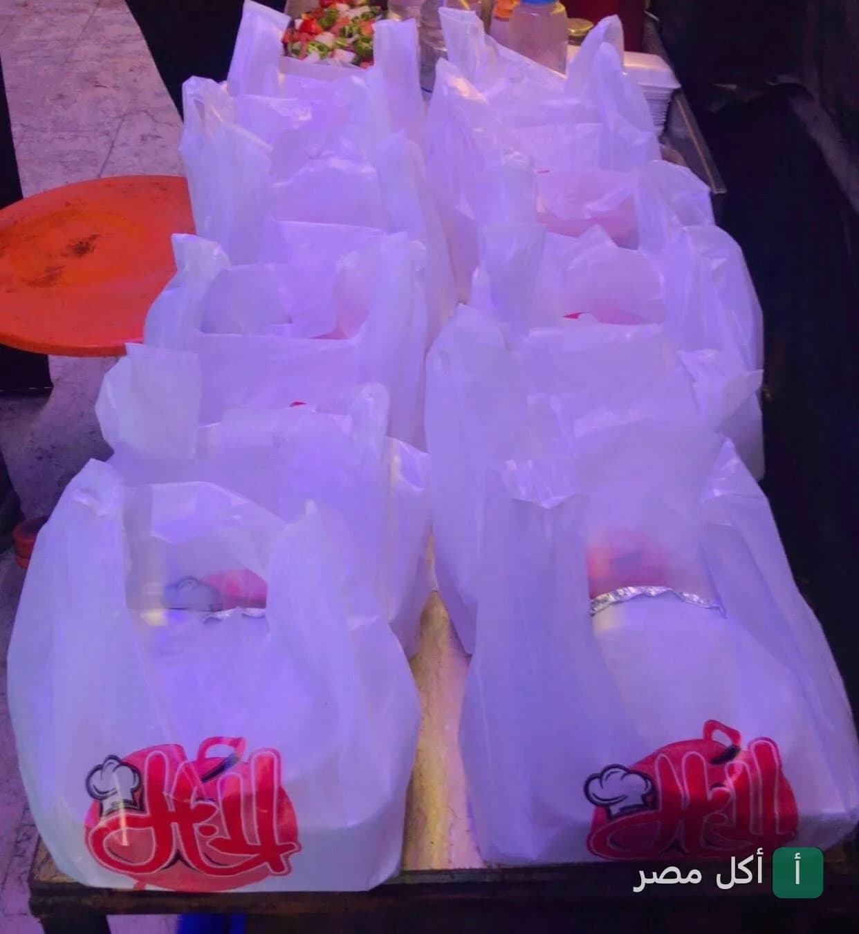 أكياس بلاستيك بيضاء مطبوع عليها شعار مطعم الخال في إمبابة جاهزة للتوصيل