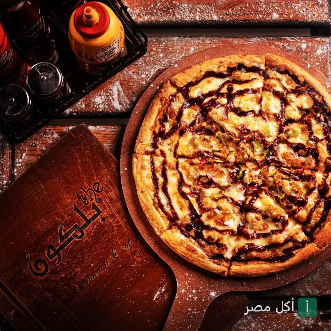 بيتزا بصوص الباربكيو على لوح تقديم خشبي يحمل شعار ذا بلكون كافيه في الشيخ زايد.
