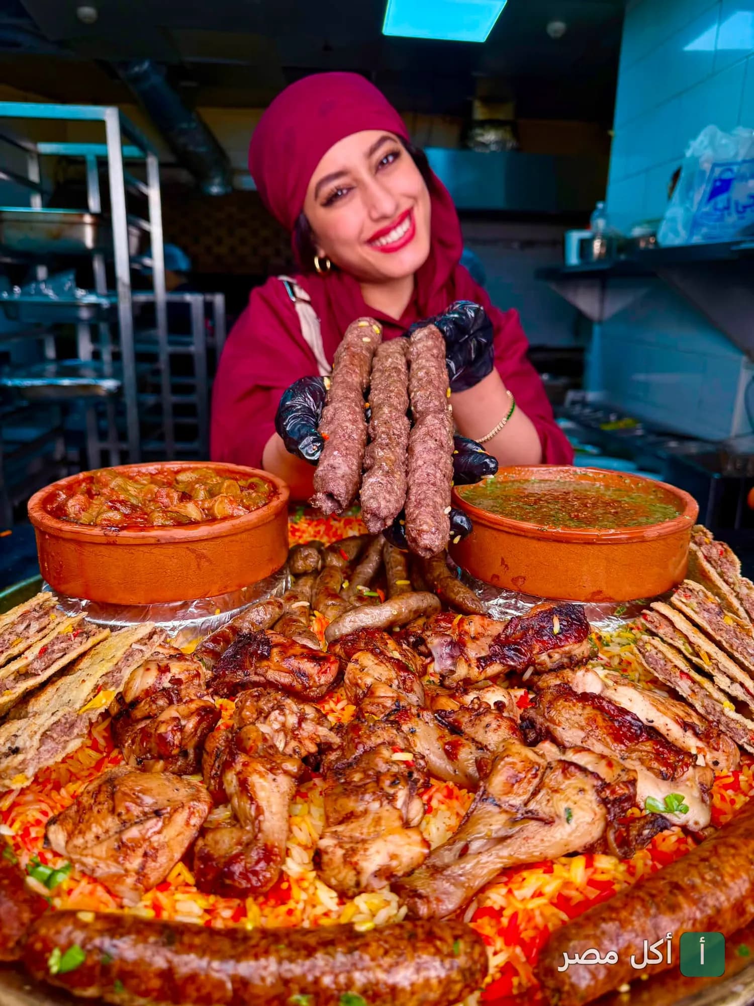 طباخة في مطعم بيت لحم بالشيخ زايد تقدم طبق مشاوي مشكل مع أرز وطواجن شرقية.
