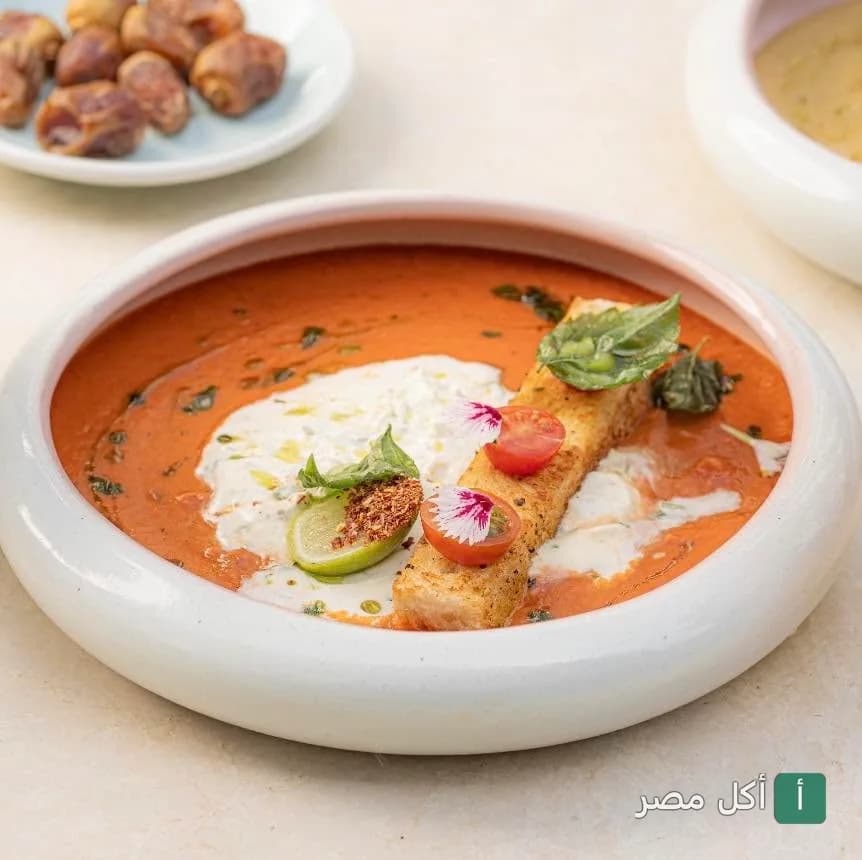طبق شوربة طماطم كريمية مزينة بالكريمة وقطعة خبز محمص في مطعم برانش آند كيك ببارك ستريت
