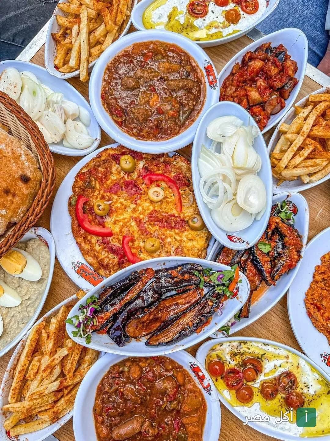 سفرة فطار مصري متنوعة من مطعم نور للفول والطعمية بالشيخ زايد تضم أطباق فول، مسقعة، أومليت، وبطاطس محمرة.