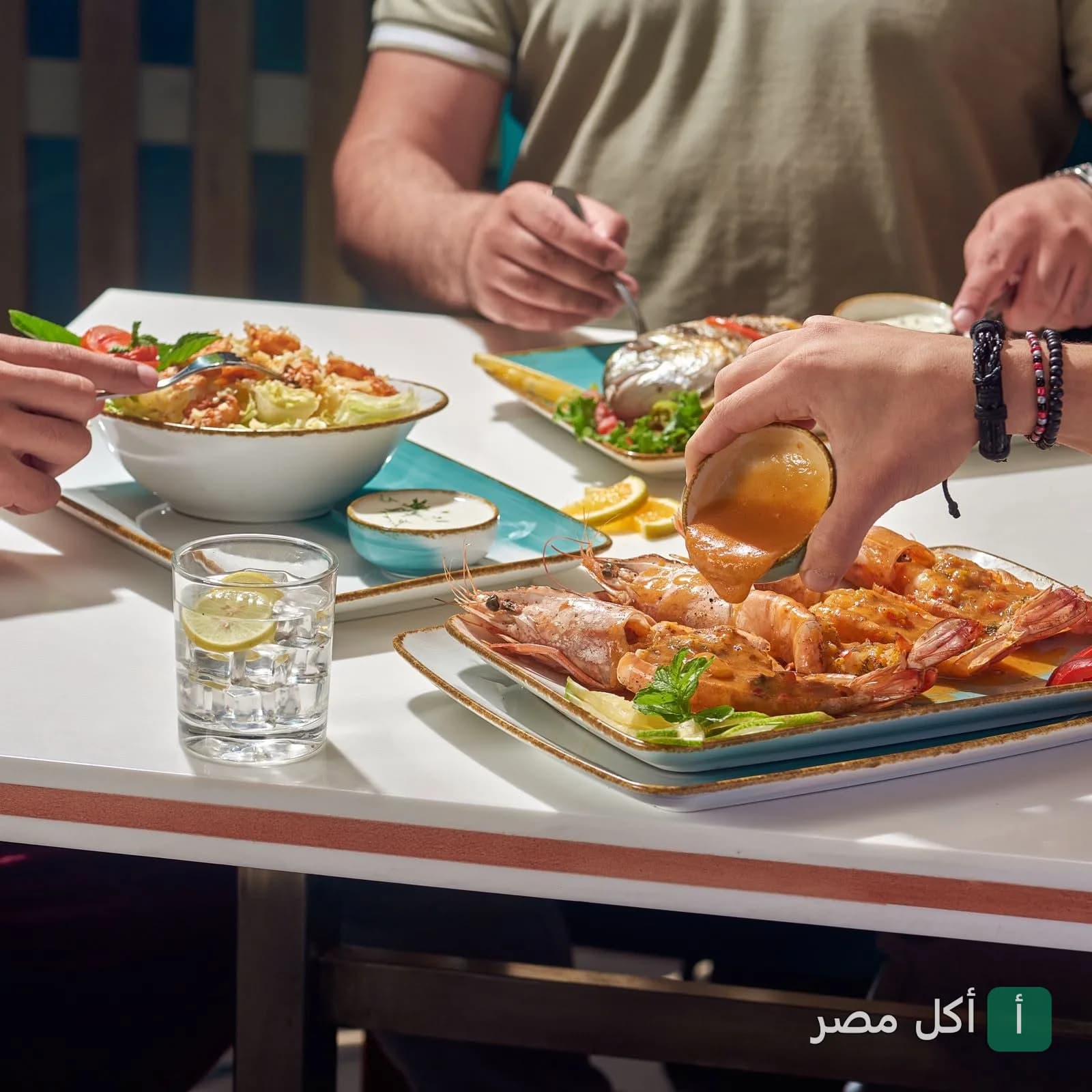 أشخاص يتناولون أطباق الجمبري والأسماك البحرية في مطعم قدورة بأمريكانا بلازا في الشيخ زايد.