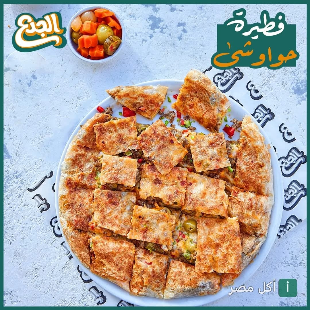 فطيرة حواوشي مقطعة في طبق من مطعم الجدع بالشيخ زايد مع طبق مخلل جانبي.