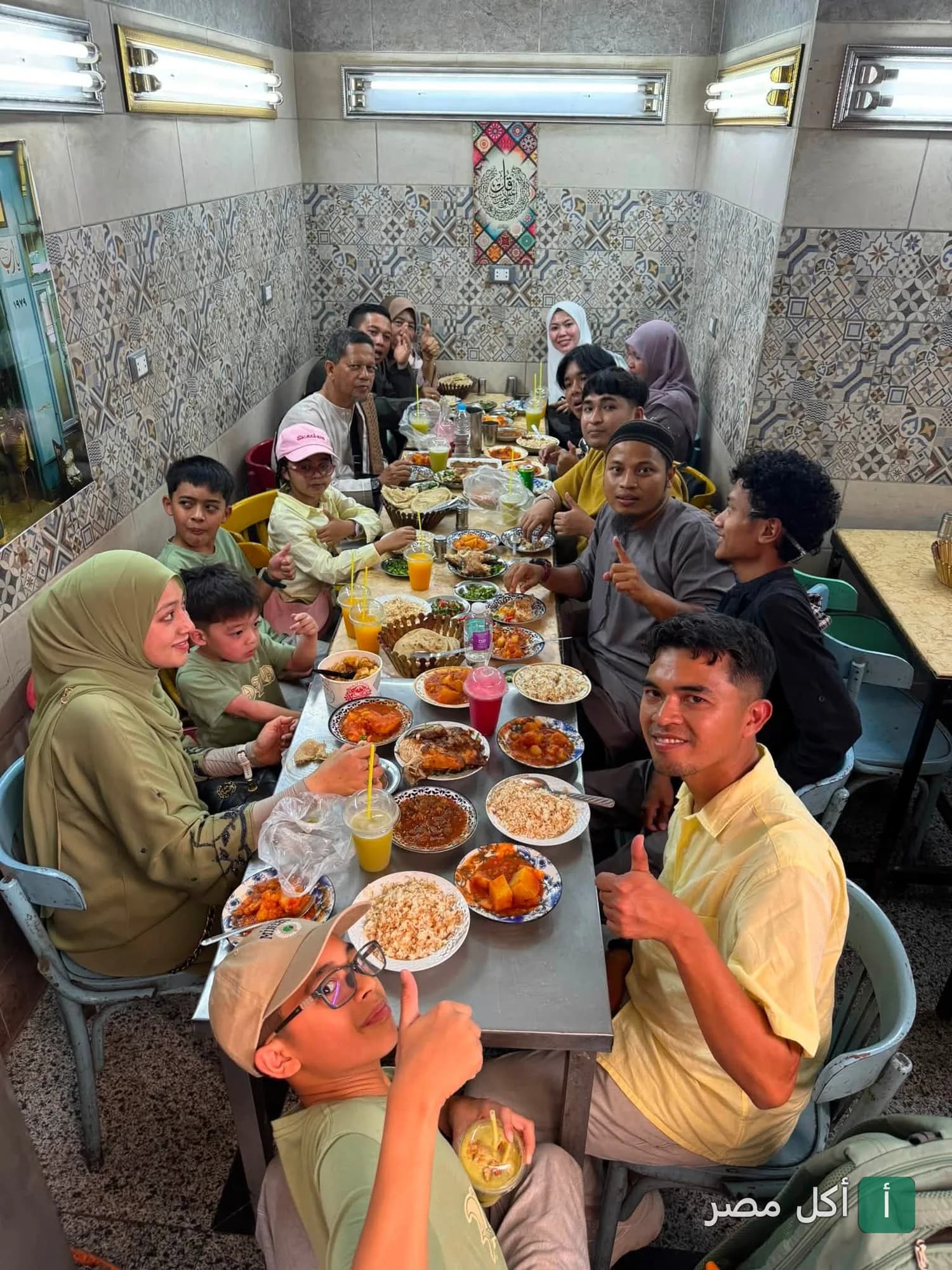 مجموعة من الأشخاص يتناولون وجبات منزلية متنوعة على طاولة طعام داخل مطعم عم توفيق في عابدين.