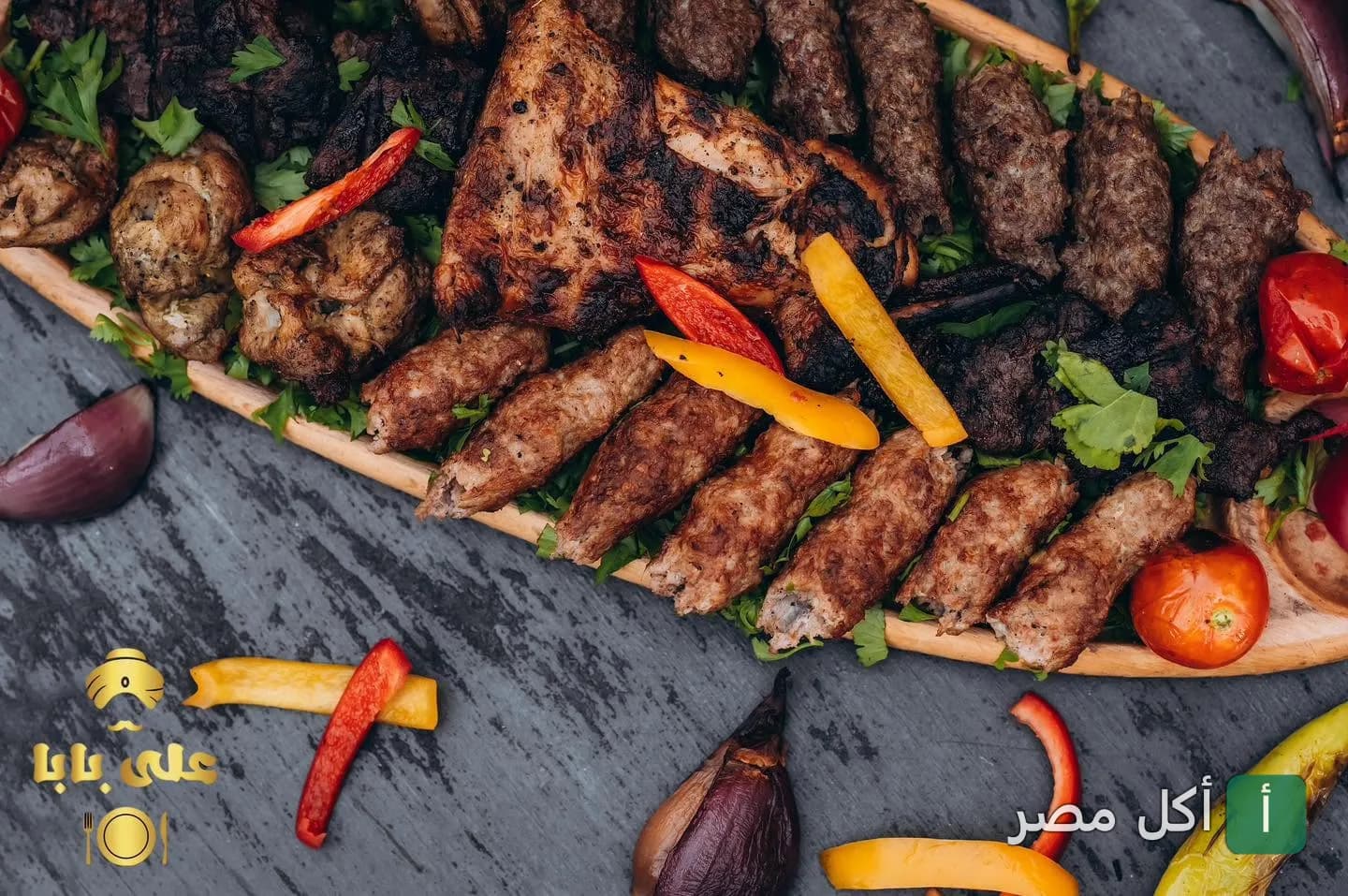 طبق مشويات مشكل يضم كفتة وقطع دجاج مشوية مزينة بالخضروات في مطعم علي بابا بعابدين.
