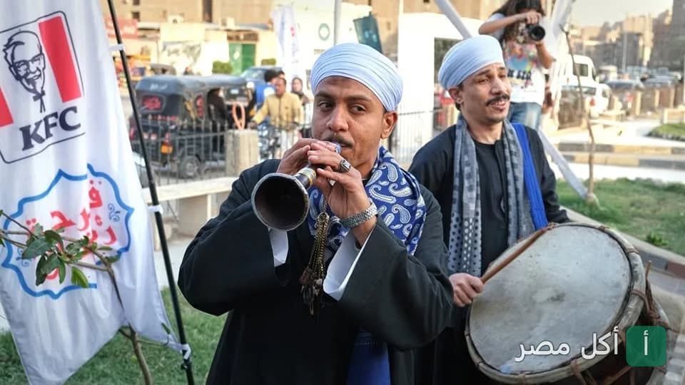 عازف مزمار وطبال بزي تقليدي أمام علم كنتاكي في أمريكانا هَب داون تاون