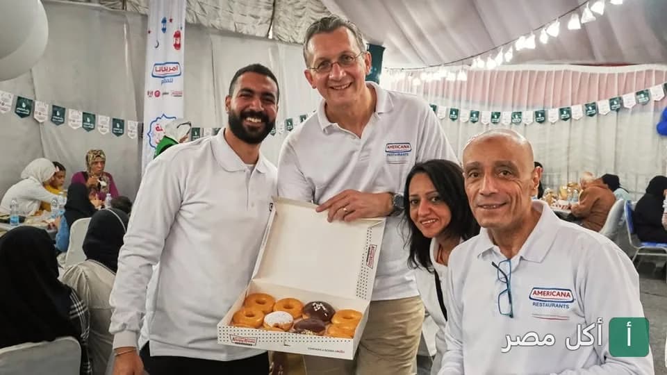 فريق عمل أمريكانا هَب في داون تاون فود كورت يقدمون علبة دونتس كريسبي كريم للضيوف.