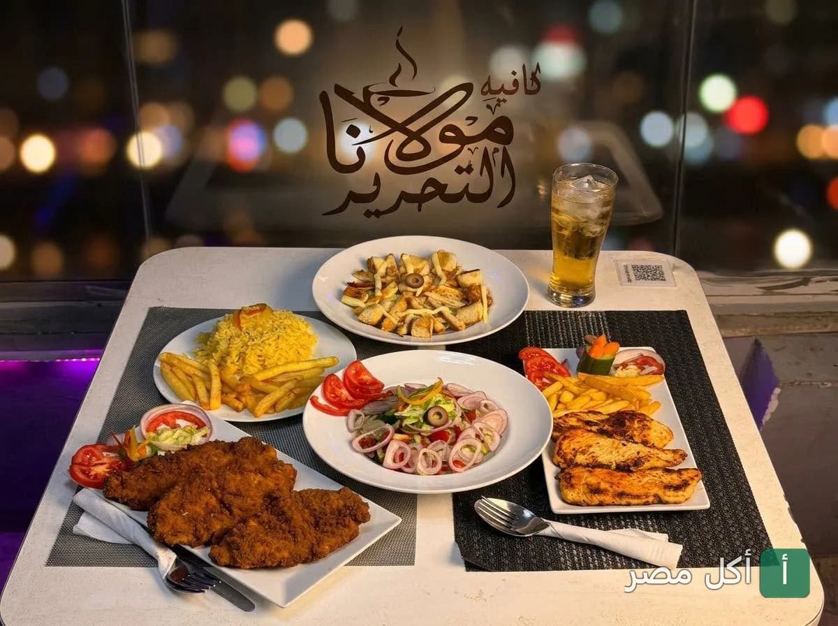 سفرة متنوعة من أطباق الدجاج والمقبلات في مطعم مولانا بعابدين مع إضاءة ليلية في الخلفية.