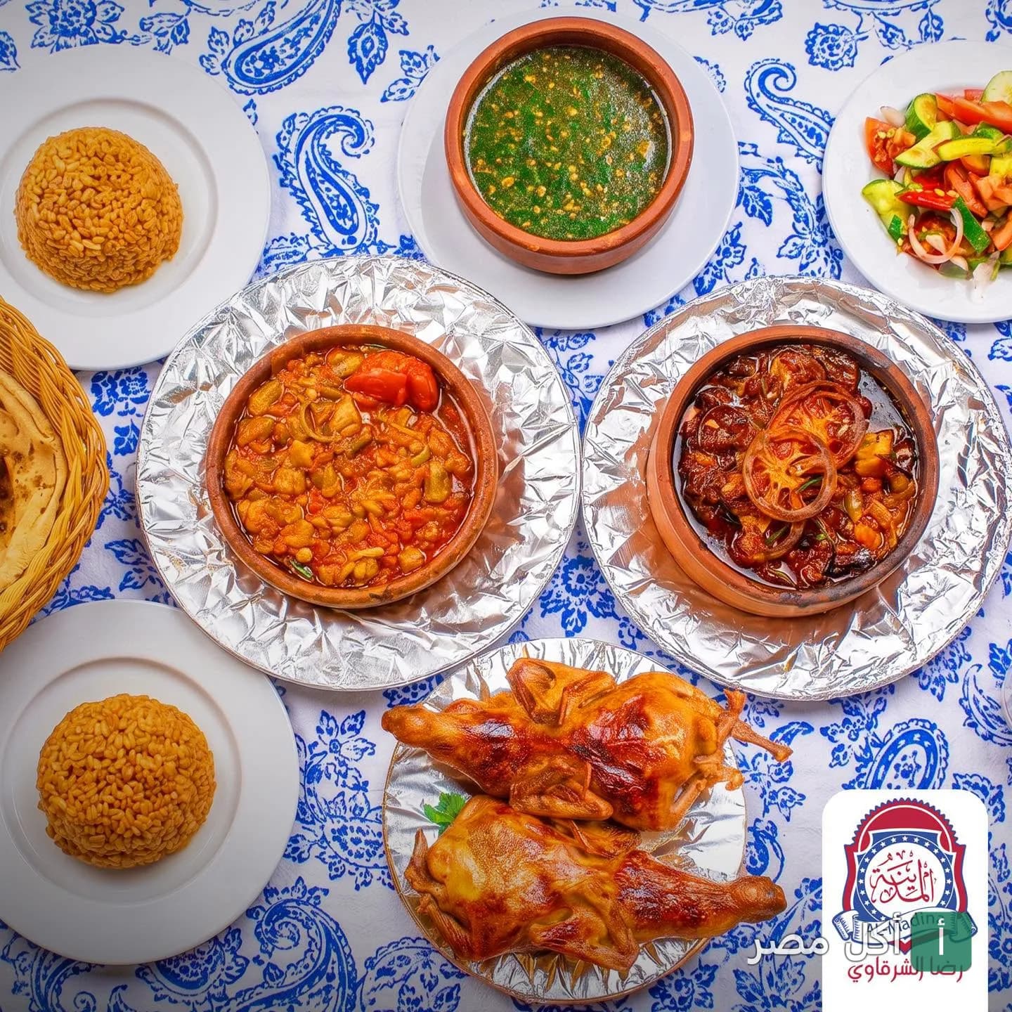 سفرة مصرية متنوعة من مطعم المدينة – رضا الشرقاوي بعين شمس تضم طواجن خضار، ملوخية، أرز، وحمام محمر.