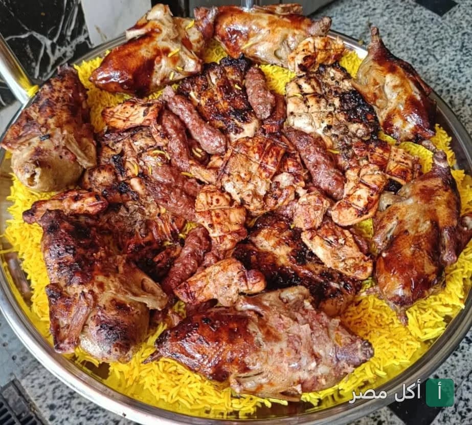صينية مشويات متنوعة من مطعم عبد الباسط عبد الصمد في عين شمس، تضم حمام محشي وكفتة وقطع دجاج مشوية على أرز أصفر.